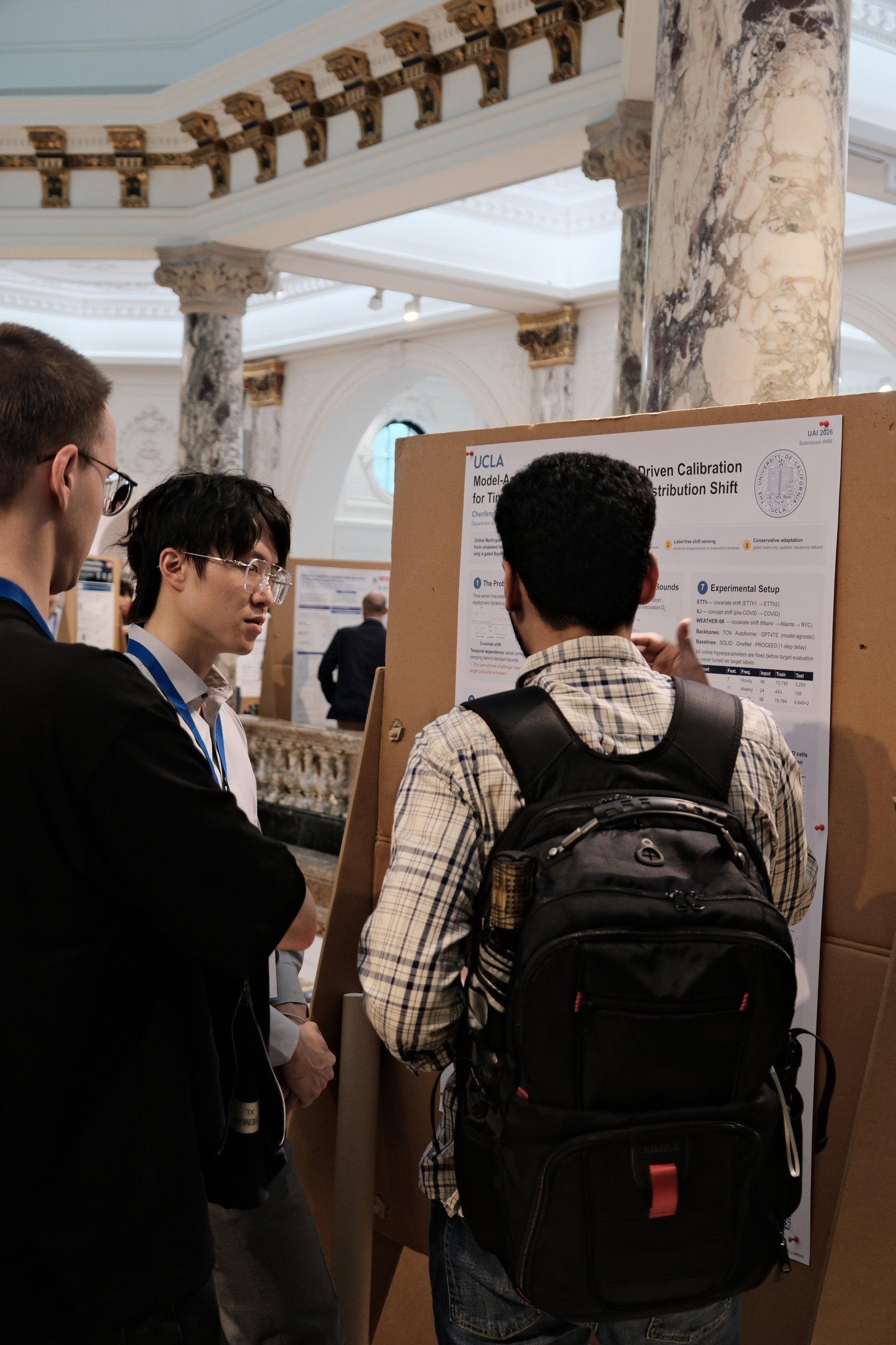Explaining the OMPB poster in the Marble Hall at UAI 2026